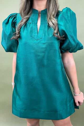 Teal dress with puff sleeves worn by a person on a green background