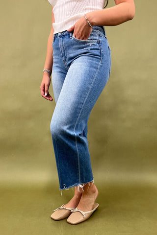 Person wearing blue jeans and a white top on a green background