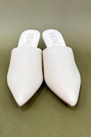 Pair of white pointed-toe shoes with 'BEAC' branding on a beige background