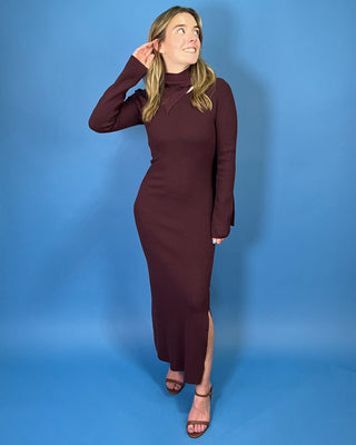 Deep burgundy ribbed knit maxi dress with long sleeves, a fitted silhouette, side slit, and chic asymmetrical cutout mock neckline.