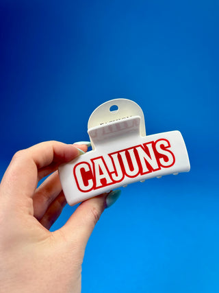 White oversized Cajuns claw hair clip with bold red lettering, durable spring hinge, and strong grip teeth for secure everyday styling.