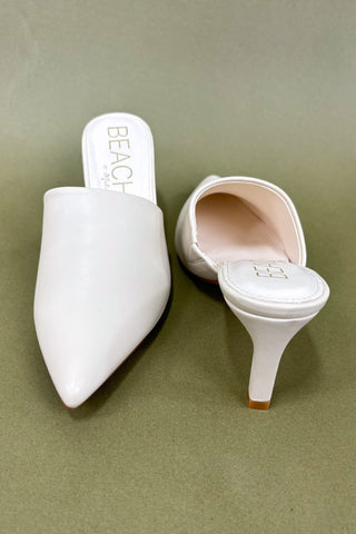 White pointed-toe shoes with 'BEACH' branding on a green background