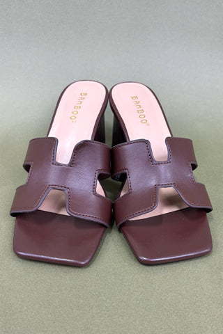 Pair of brown sandals with a heart design on a green background