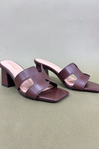 Pair of brown high-heeled sandals on a light gray background