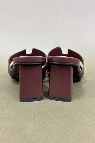 Pair of maroon shoes on a beige surface
