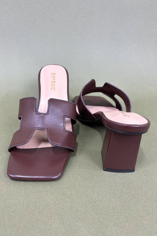 Pair of brown high-heeled sandals on a light gray background