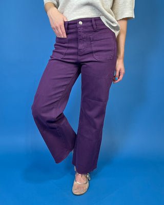 Deep purple high-rise wide leg jeans with front patch pockets, a flattering structured fit, and trendy raw hem detailing.