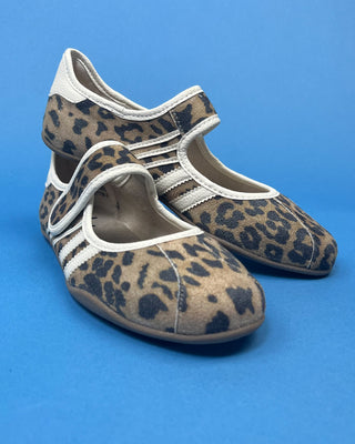A pair of Mary Jane shoes with a brown and black leopard print pattern and white stripes, displayed on a solid blue background.