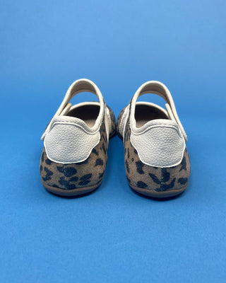A pair of Mary Jane shoes with a brown and black leopard print pattern and white stripes, displayed on a solid blue background.