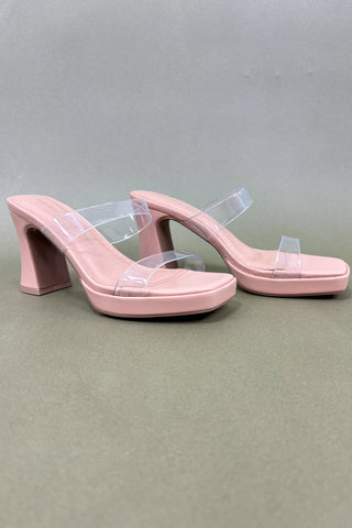 Pair of pink high-heeled shoes with clear straps on a gray background