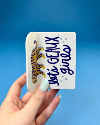 White oversized LSU-inspired claw hair clip featuring a "Let's Geaux Girls" design with purple and gold accents and a secure spring hinge.