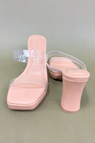 Pink high-heeled shoes with clear straps on a gray background