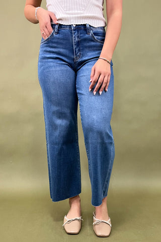 Person wearing blue jeans and a white top on a green background