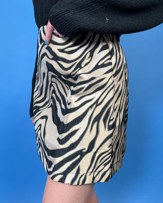 Black and metallic gold zebra print mini skirt with a sleek fitted silhouette and bold statement-making animal print design.