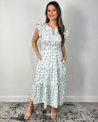 Model wearing a white floral tiered midi dress with flutter sleeves and a smocked waist, styled with nude block-heel sandals.