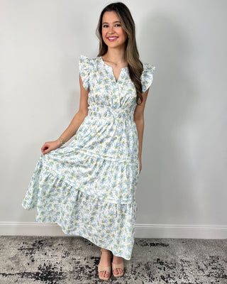 Model wearing a white floral tiered midi dress with flutter sleeves and a smocked waist, styled with nude block-heel sandals.