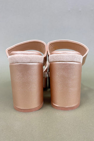 Pair of rose gold sandals on a gray background