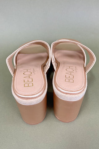 Pair of beige sandals with 'BEACH' branding on a light gray background