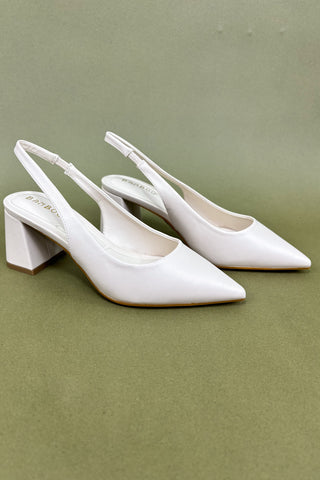 Pair of white high-heeled shoes on a green background