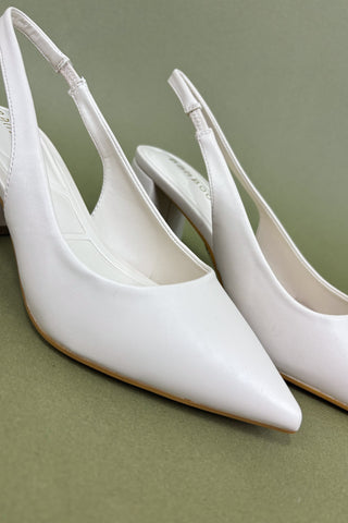 White pointed-toe shoes on a green background