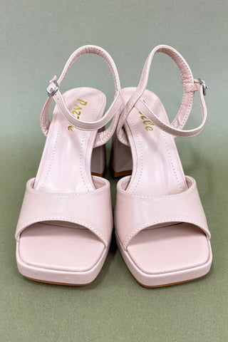 Pair of light pink high-heeled sandals on a green background