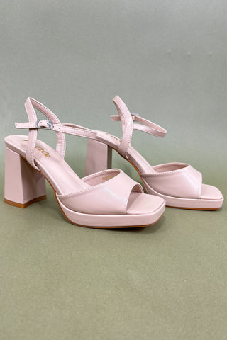 Pair of pink high-heeled sandals on a green background