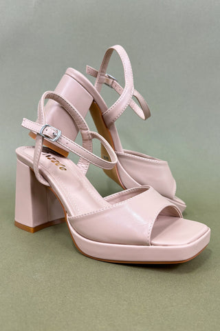 Pink high-heeled sandals on a green background