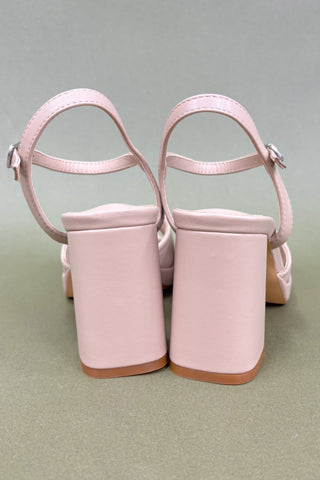 Pair of pink high-heeled shoes on a light gray background