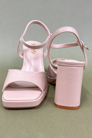 Pink high-heeled sandals on a green background