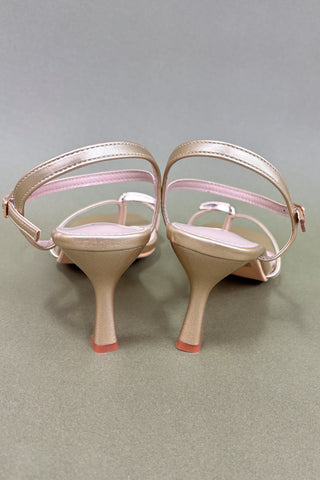 Pair of high-heeled shoes with pink straps on a gray background