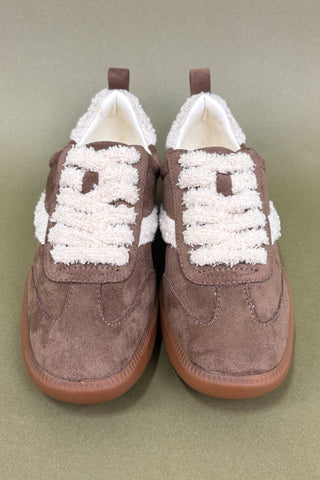 Pair of brown shoes with white laces on a beige background