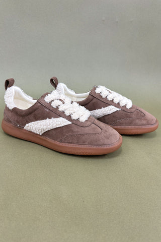 Brown sneakers with white laces on a green background