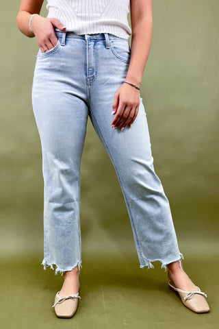 Person wearing light blue jeans and beige shoes on a green background
