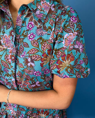 Teal floral mini dress with pink and brown print, short sleeves, button-front detail, and ruffled hem.
