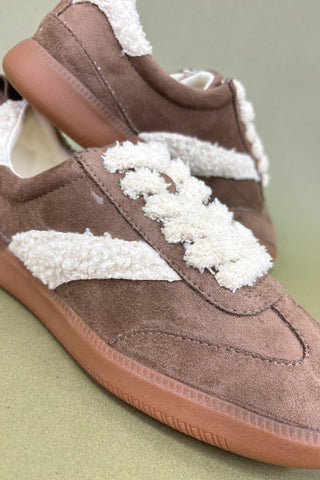 Brown sneakers with white laces on a light green background