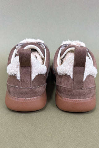 Pair of brown shoes with white soles on a beige background