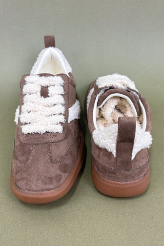 Pair of brown shoes with white fur lining on a green background