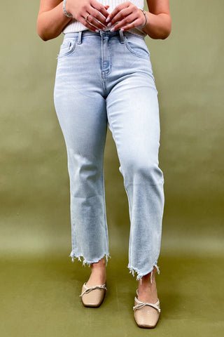 Person wearing light blue jeans on a green background