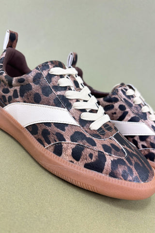Leopard print sneakers with white laces on a light green background