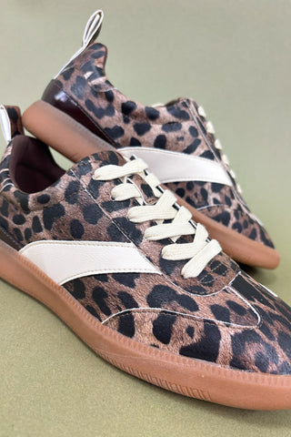 Leopard print sneakers with white laces on a green background