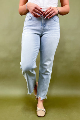 Person wearing light blue jeans on a green background
