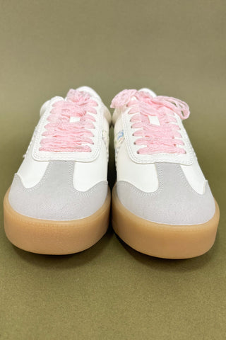 White sneakers with pink laces on a beige background