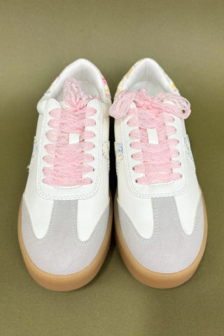 White sneakers with pink laces on a green background