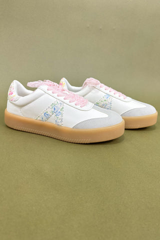 White sneakers with floral patterns and pink accents on a beige background