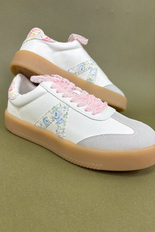 White sneakers with floral patterns and pink laces on a beige background