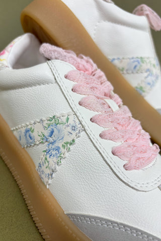 White sneaker with floral embroidery and pink fuzzy details on a light background
