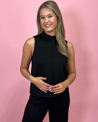 Woman wearing a black sleeveless top against a pink background
