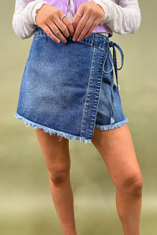 Person wearing a blue denim skirt on a plain background