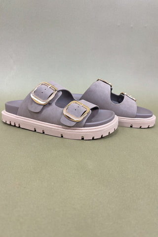 Gray sandals with gold buckles on a light green background