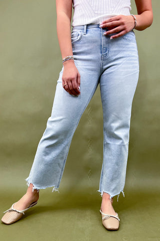 Person wearing light blue jeans and white top on a green background